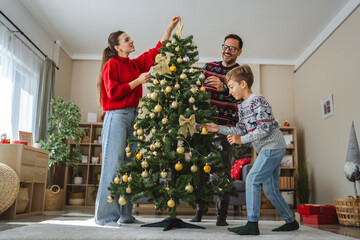 Happy family decorating christmas tree together at home
