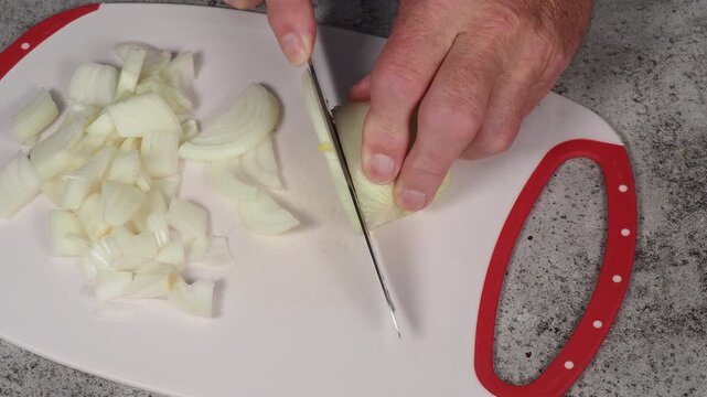Hands of a cook cutting a large onion into slivers on a white cutting board with cutting sounds