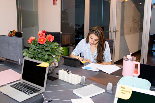 Office worker uses a digital tablet sitting at a desk in a coworking