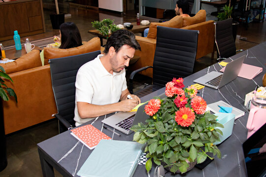 A freelancer concentrating on work at a communal desk in a coworking
