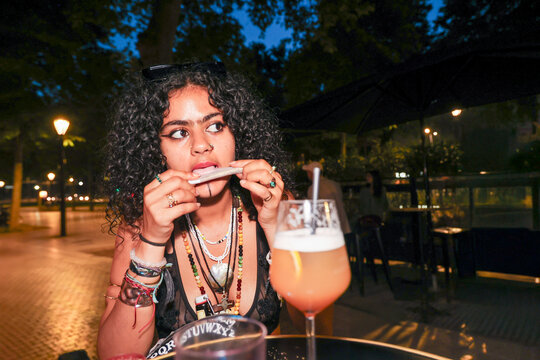Woman Enjoying a Drink and rolling a joint Snack at night