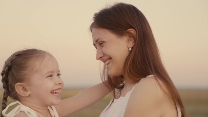 happy mother and daughter hugging while walking in nature together, little daughter laughs while sitting in her mother's arms, good family mood, kid and parent love each other, baby childhood dream.