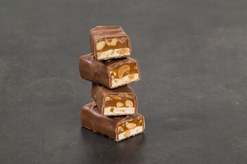 Chocolate bar. Nougat, caramel with peanuts, in chocolate. Dark background. Close up	