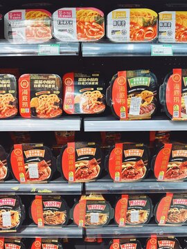 29.05.2025, Kuala Lumpur, Malaysia.Rows of packaged instant hot pot meals with red and black designs stacked on supermarket shelves. Various meat and spicy flavors. Ready-to-eat hot pot.
