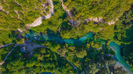 Aerial view of Blue Eye spring in Albania with turquoise river flowing through dense green forest stunning natural attraction and travel destination