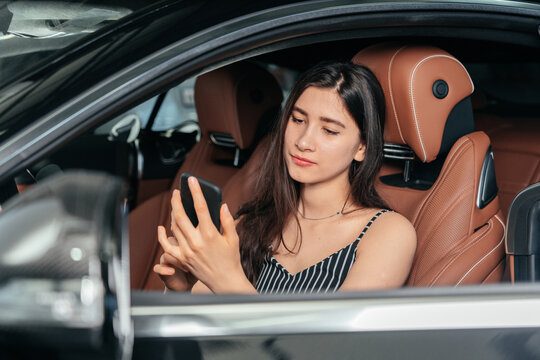 Young attractive asian woman using phone while sitting in a luxury car front sea - Powered by Adobe