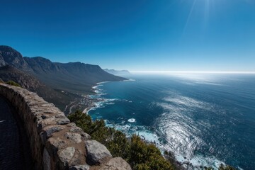 Obraz premium Expansive ocean vista from a high vantage point, showcasing rugged coastal mountains and a clear blue sky.