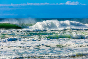 Photograph of waves from the Tasman Sea crashing onto Jones Beach against a blue sky near the town of Kiama Downs in the Illawarra region on the south coast of NSW, Australia.