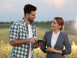 Woman and farmer looking at each other while doing business in field