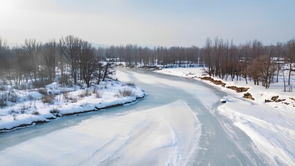 Frozen river winding through snowy winter landscape with bare trees