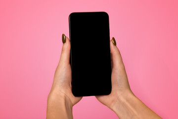 Modern smartphone with black blank screen for mockup in woman's hands on yellow studio background, top view with empty space. Free space for your text, logo or design