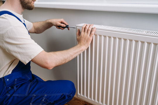 Plumber repairing home radiator for efficient winter heating in living room
