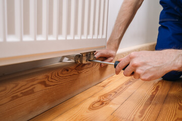 Home heating radiator maintenance by a plumber in modern living space