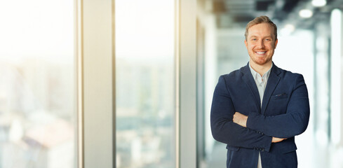 Fototapeta premium Cheerful man business professional stand in a modern office setting. He is wearing business attire and appear confident and successful, copy space