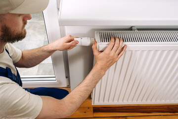 Plumber installing a modern radiator for efficient home heating during winter