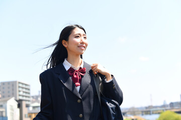 日本の女子高生が青空の下で笑顔で通学する
