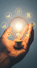 Hand holding illuminated lightbulb with surrounding business icons, showcasing innovation, ideas, and strategic solutions for growth and partnership