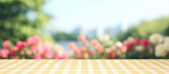 Obraz premium Yellow Checkered Tablecloth with Blurred Floral Background