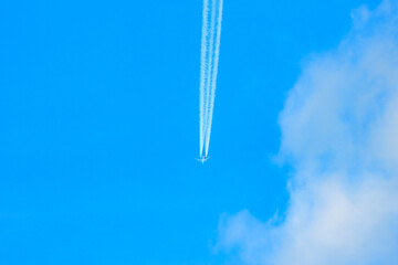 Jet airplane at high altitude leaving long contrail in clear blue sky, vapor trail phenomenon related to aviation emissions, atmosphere and climate impact concept