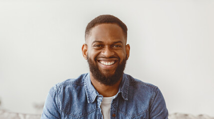 Portrait of cheerful young attractive african american male with beard look at camera in room...