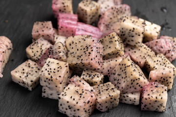 diced ripe red pitaya with lots of small black seeds and white soft sweet flesh inside, sweet ripe...