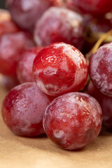 a branch of red ripe grapes in drops of water on the table, wet ripe and delicious red grapes on the table before cooking
