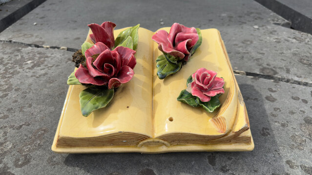 Vintage ceramic funeral plaque shaped like a book with roses on a grave