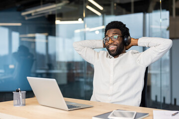 Obraz premium Happy manager relaxing listening to music in headphones at workplace