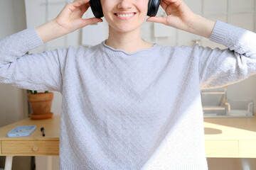 Happy girl listening to music online with wireless headphones from smartphone. Woman is having fun with music with a phone and headphones. Girl uses wireless earphones