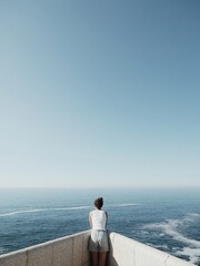 A girl on a stone balcony high up on the cliff with the sea and sky in the background. 