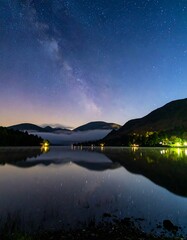 Night sky reflecting on a lake, mountains in the background