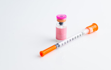 Small Pink Vial Next to Single Use Syringe on Light Background