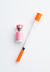 Small Pink Vial Next to Single Use Syringe on Light Background