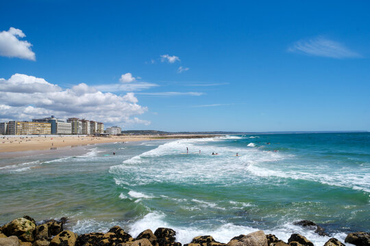 Lissabon Strand von Costa da Caparica offers serene views of waves and vibrant beach activities on a sunny day in Portugal