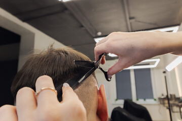 Woman Barber making customer Fashionable haircut in Modern style barbershop. Male hair cutting with scissors close up. Bearded Man client visit gentleman grooming beauty salon for hairstyle care