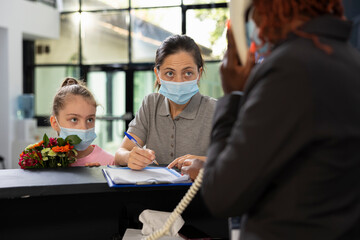 African american employee gives visiting list forms to visitors to sign, sweet girl and their...
