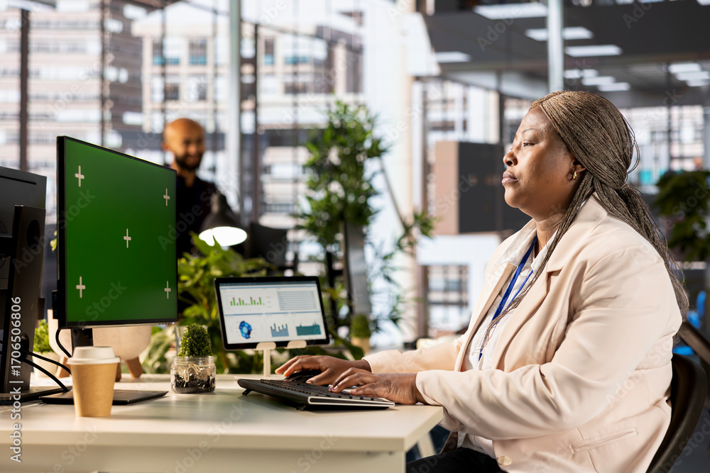 Poster company worker studies performance metrics next to green screen, networking and examining data analy