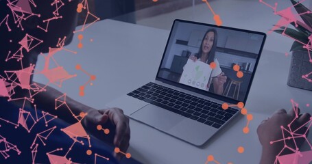 Women in blue shirt and dark top viewing laptop in home office, with printed diagram sheet