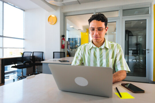 Focused Young Man Using Laptop in Co-work Space