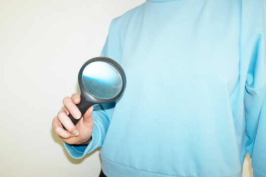 Fototapeta Hand holding magnifying glass with zooming lens with hard flashlight