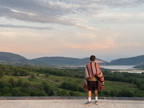 Anonymous guy looking over mountains under sunset sky