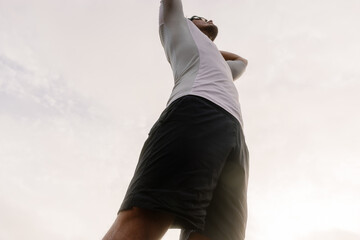 A runner standing with hands over his head pausing to catch breath