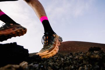 A trail runner’s feet stepping on rocky volcanic ground