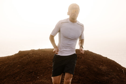 Medium shot against the light of a trail runner trekking in a volcano