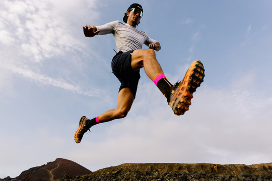 Trail runner taking a long stride while jumping between rocks