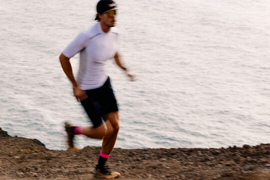 Blurred view capturing trail runner moving quickly along a rocky hill