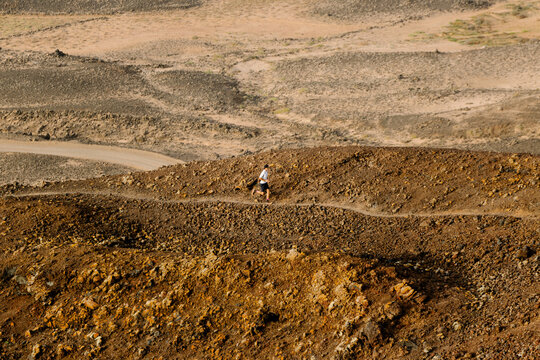 Desert landscape with a trail runner running along a rocky trail