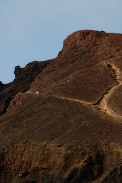 A volcanic landscape with a wild horse trotting through a rocky trail