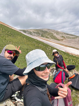 Selfie of three hikers sitting on summit of a mountain