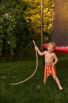Joyful boy playing with garden hose